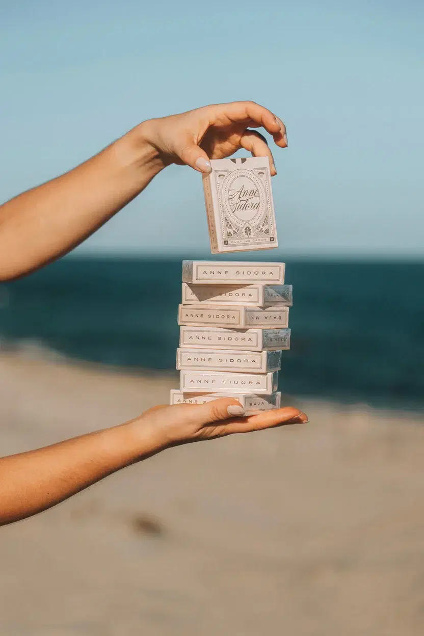Hands holding a stack of branded departure gift boxes against a coastal backdrop